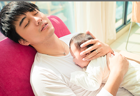 This dad is sleeping in a chair that lays back. Now the baby is sleeping on his tummy with his face pressed into dad's chest.